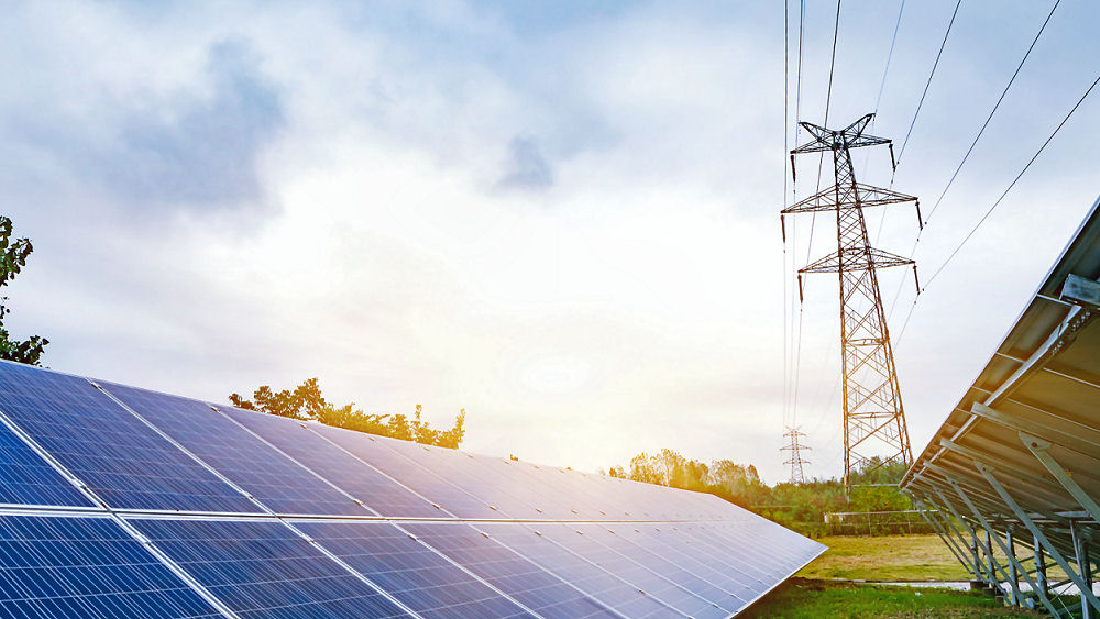 Solar panels and power lines with sunset in background