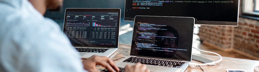 developer testing code on 3 monitors