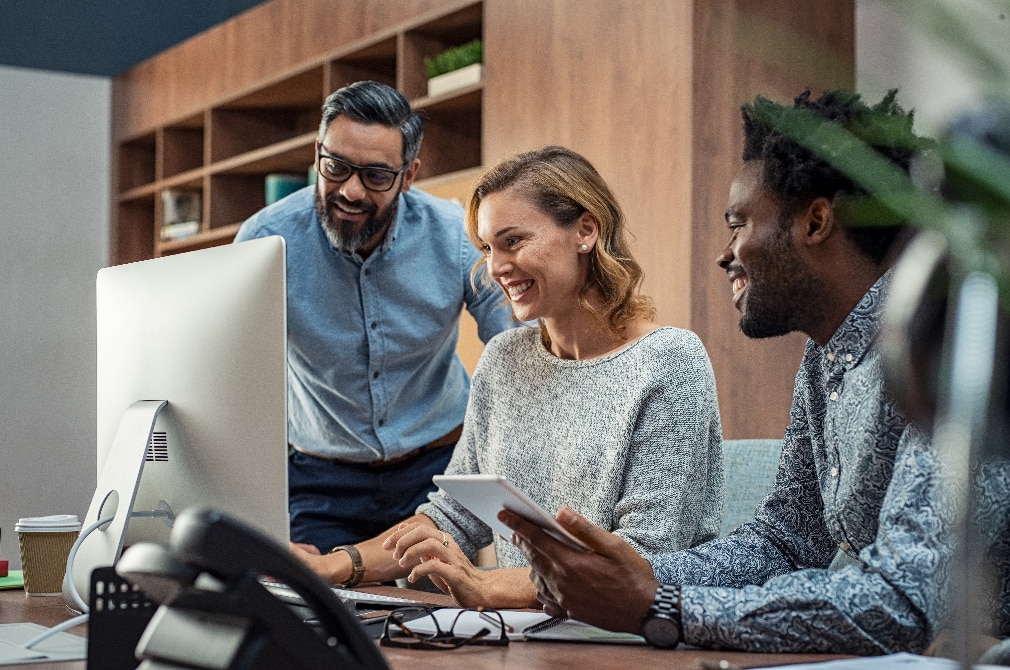 Three professionals looking at a computer screen
