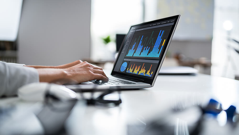 hands typing on keyboard with data on computer screen
