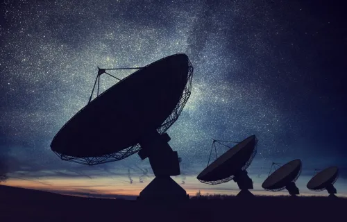 A group of satellite dishes inb a field pointing to space