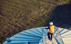 aerial view of an industry worker standing on top of a silo