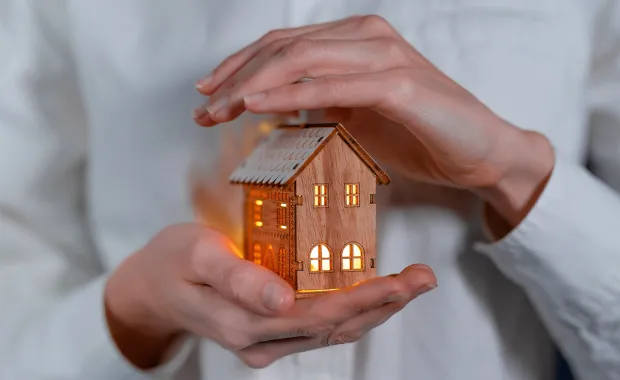 person holding a lighted model of a wooden house