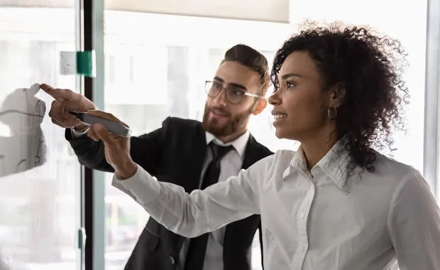 Two professionals exchanging ideas on a whiteboard