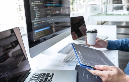 IT-Experte sitzt vor drei Monitoren