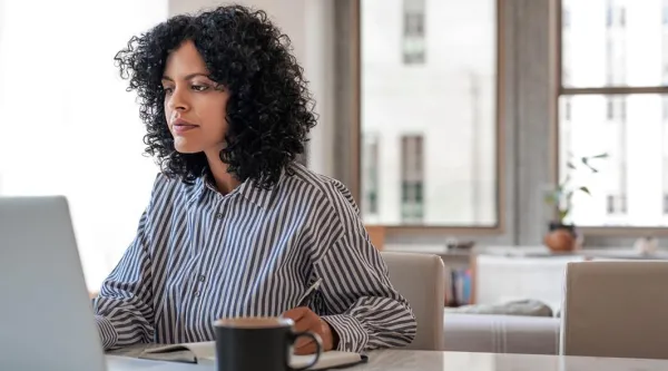 Consultant works on laptop at desk using machine learning to predict cracks in steel