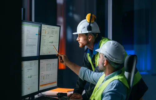 Two utilities workers looking at data o computer screen in an OT environment