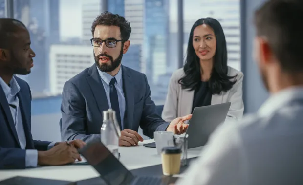 Professionals sitting around a desk discussing strategies and business goals
