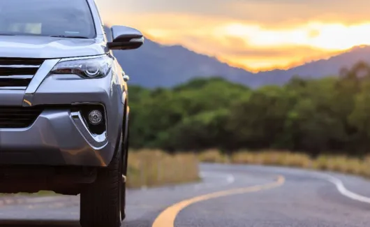 close-up of an automobile on a highway with the sunset in the background