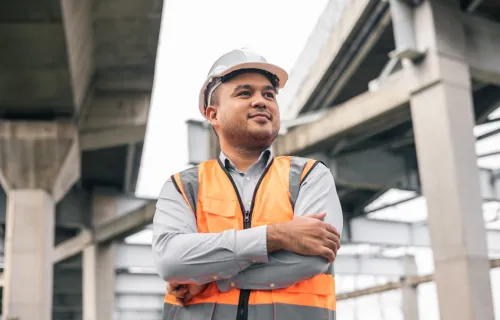 Male field service worker on construction site wearing hard hat and high-vis jacket 