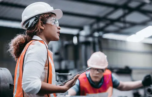 Industrial engineer wearing a white helmet while standing in a heavy industrial factory