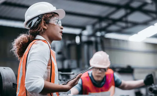 Industrial engineer wearing a white helmet while standing in a heavy industrial factory